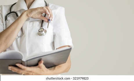 Front View Of Female Doctor With Stethoscope Around Her Neck  About To Take A Pen From A Pocket Of Her White Medical Jacket To Make A Note Or Observation In A Notebook.