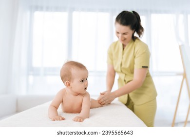 Front view of female therapist massaging toddler protecting from dysplasia. Adorable infant little boy getting gymnastics exercise, massaging feet and legs from masseuse. Concept of infant healthcare - Powered by Shutterstock