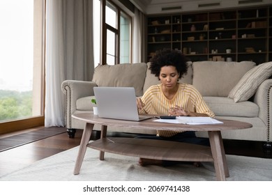 Front View Focused Young African American Woman Managing Household Budget, Planning Investments, Paying For Insurance Utility Bills Taxes Online Using Computer E-banking Application At Home.