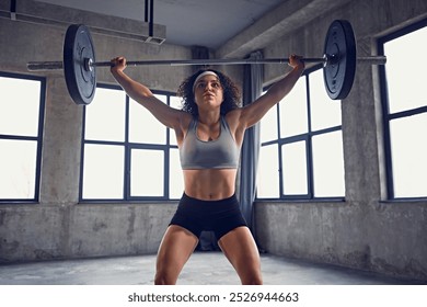 Front view of focused young athlete woman in sportswear doing squat technique with barbell overhead in motion at gym. Concept of professional sport, active lifestyle, bodybuilding, action. Ad - Powered by Shutterstock