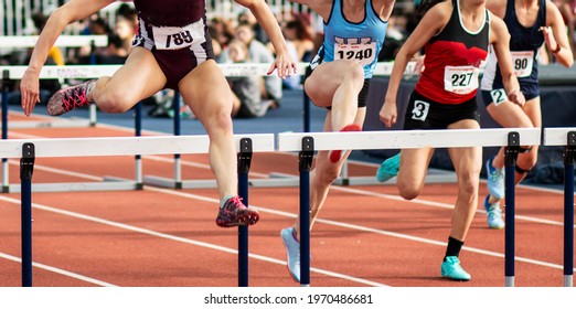 Front view of four high school girls running in a hurdle track and field race. - Shutterstock ID 1970486681
