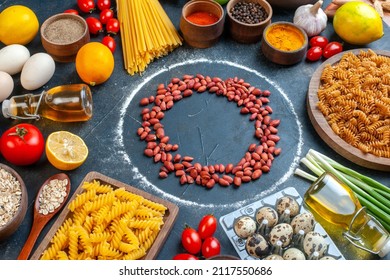 front view fresh peanuts in circle around eggs vegetables pasta and seasonings on dark background raw health diet color meal photo