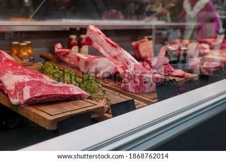 Front view of fresh raw red good quality of meat through glass of counter at the butcher shop.