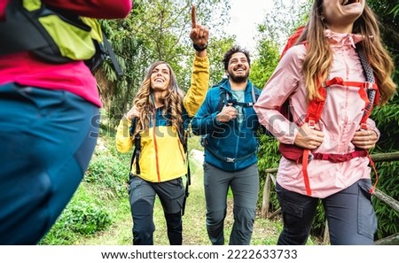 Front view of friends group trekking in forest on italian alps - Hikers with backpacks walking around wild mountain woods - Wanderlust travel concept with young people at excursion - Warm vivid filter