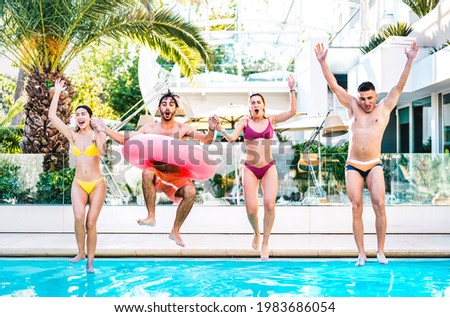 Front view of friends jumping in swimming pool with lilo airbed at luxury resort party - Life style vacation concept with happy guys and girls having fun games in summer day - Bright vivid filter