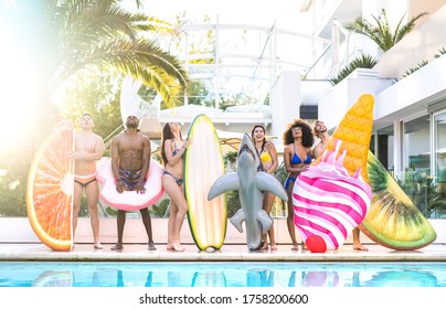 Front view of friends at swimming pool party with lilo airbed and swim wear - Youth vacation concept with happy guys and girls having fun in summer day at luxury resort - Warm bright saturated filter