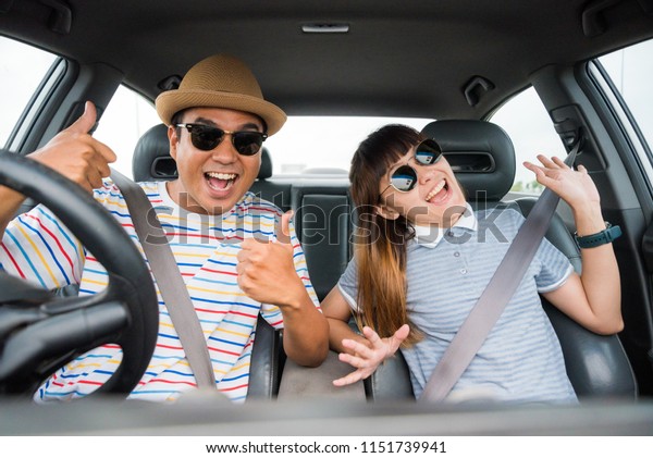 Front view of Funny moment\
couple asian man and woman sitting in car. Enjoying travel\
concept.