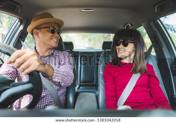 Front view of Funny moment\
couple asian man and woman sitting in car. Enjoying travel\
concept.
