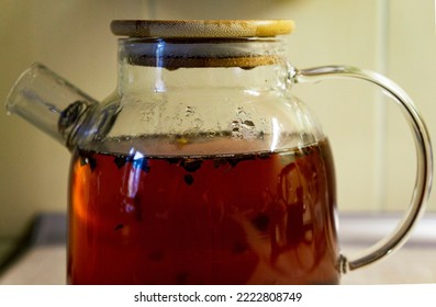 Front View Of A Glass Teapot Full Of Black Tea. Cozy Home Environment.