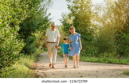 Front View Of Grandparents And Grandchild Walking On A Nature Path