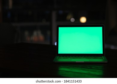 Front View Of Green Screen Laptop Computer At Dark Night.