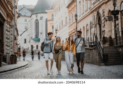 Front view of group of happy young people with drinks outdoors on street on town trip, laughing. - Powered by Shutterstock