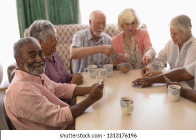 Front view of group of senior people playing cards around table in living room at nursing home - Powered by Shutterstock