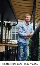 Front view of guy in jeans that stands in the cafe at daytime.