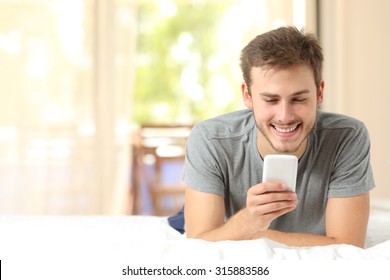 Front View Of A Guy Using A Mobile Phone In The Bedroom At Home