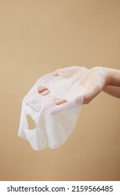 Front View Of Hand Holding A Mask In Beige Background For Cosmetic Advertising 