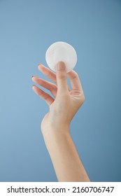 Front View Of Hand Model Holding Cotton Pad In Blue Background For Cosmetic Advertising	