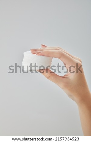 Front view of hand using cotton pad on white background 