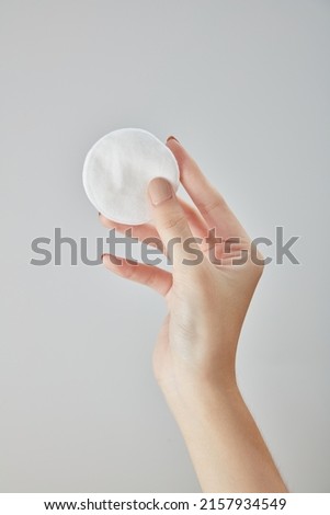 Front view of hand using cotton pad on white background 