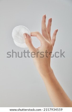 Front view of hand using cotton pad on white background 