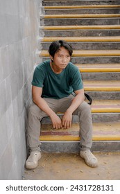 front view of a handsome Javanese man sitting on the steps.