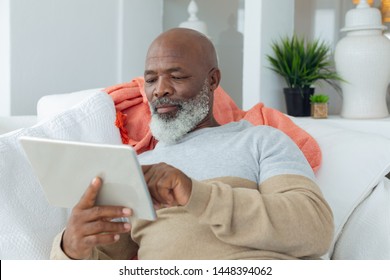 Front view of handsome senior African american man using a digital tablet on sofa in beach house. Authentic Senior Retired Life Concept - Powered by Shutterstock