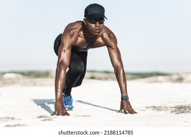 Front View Of A Handsome Young Muscular African American Runner On Starting Blocks Ready To Race, Sprinter At The Start. Black Man Athlete In A Running Run Outdoors In Nature In The Mountains