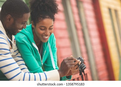 Front view of happy African American couple using digital camera while standing at beach hut - Powered by Shutterstock