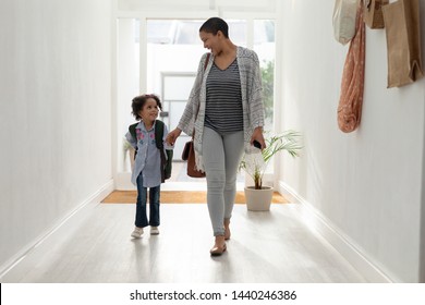 Vorderansicht des glücklichen afroamerikanischen Mädchens, bei der ihre Mutter zu Hause Hand in Hand in der Nähe der Tür geht