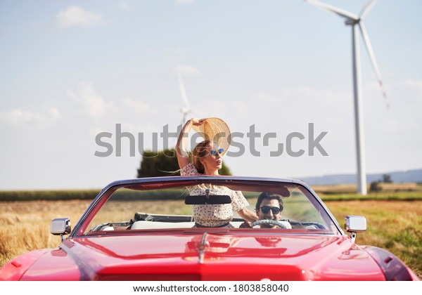 Front view of  happy couple driving in a red car   \
                          \
