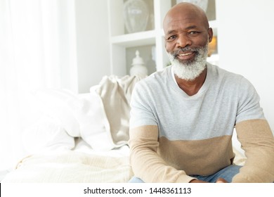 Front view of happy senior African-American man smiling while sitting on white sofa in beach house. Authentic Senior Retired Life Concept - Powered by Shutterstock