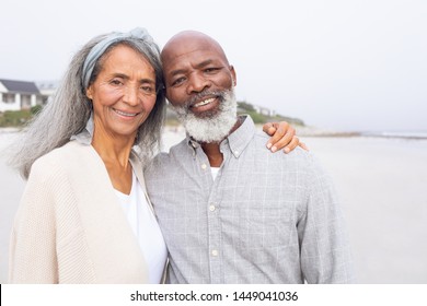 Front View Of Happy Senior African-American Couple Standing On The Beach On Cloudy Day. Authentic Senior Retired Life Concept