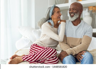 Front view of happy senior diverse couple sitting in a white room on beach house. Authentic Senior Retired Life Concept