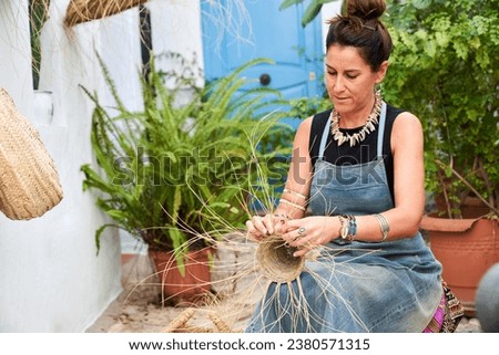 Front view of Hispanic woman weaving a basket with esparto fibers. Manual work, tradition and culture.