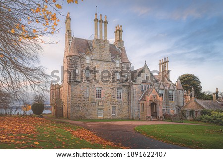 Front view of the historic tourist attraction 16th century Lauriston Castle in autumn with sunrise or sunset golden light in Edinburgh.