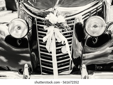 Front view of historical wedding car with ribbon and flowers. Symbol of love. Black and white photo.
