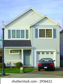 Front View Of A House With A Car Parking In Front Of Garage.