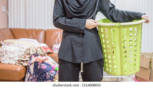 Front View Of Housewife Holding Green Empty Basket To Clean The Messy Living Room.