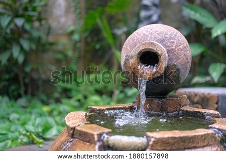 front view of Indonesia traditional clay pot or vase or vas or also called kendi as water fountain on a pond.