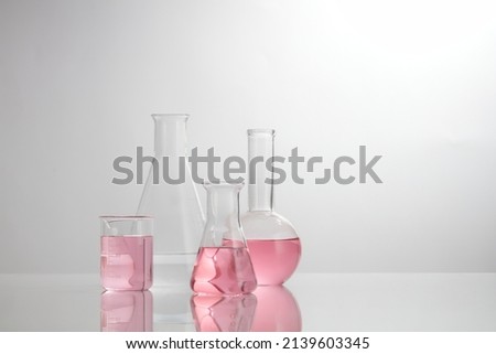 Front view of laboratory equipment filled with pink fluid in a beaker test tube in lab background for experiment advertising 