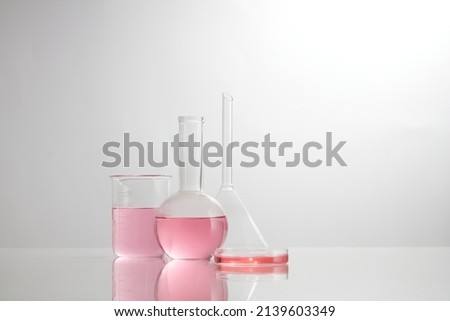 Front view of laboratory equipment filled with pink fluid in a beaker test tube in lab background for experiment advertising 