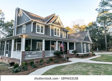 Front View Of A Large Two Story Blue Gray House With Wood And Vinyl Siding