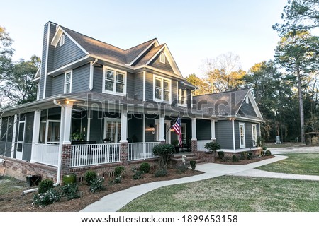Front view of a large two story blue gray house with wood and vinyl siding