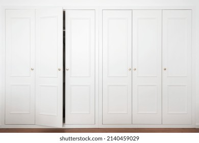 Front View Of Large White Wardrobe In American Classic Style With Ajar Door In Light Room. Advertising Of Ergonomic Furniture And Spacious Closet At Modern Apartment Interior