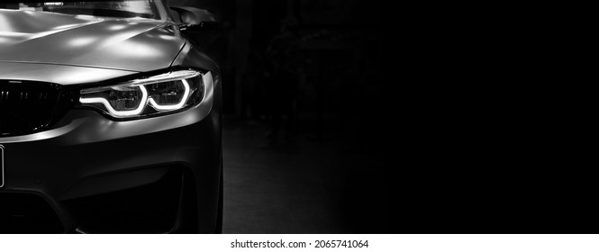 Vista frontal del coche moderno de los faros LED sobre fondo negro, espacio de copia