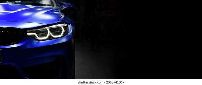 Front view of the LED headlights modern blue car on black background,
