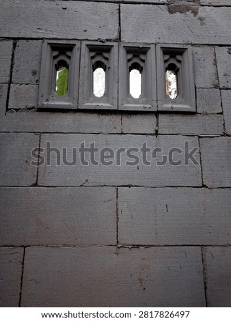 Front view of lightweight concrete block wall with four decorative air vents featuring copy space on the unpainted surface.