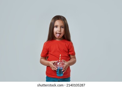 Front View Of Little Girl Licking Lips After Drinking Soda Drink From Plastic Cup With Tubule. Caucasian Female Child Looking At Camera. Childhood Concept. White Background In Studio. Copy Space