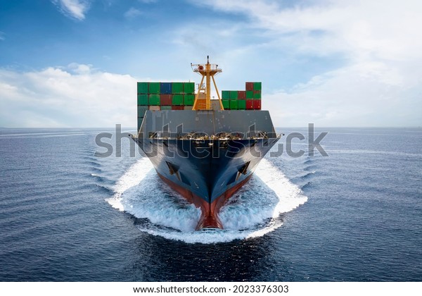Front view of a loaded container cargo vessel\
traveling with speed over blue\
ocean