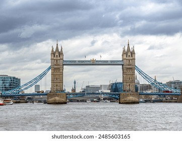 Front view of London's Tower Bridge from the River Thames with road traffic on its road and ferries sailing along the river under a cloudy sky. United Kingdom. - Powered by Shutterstock